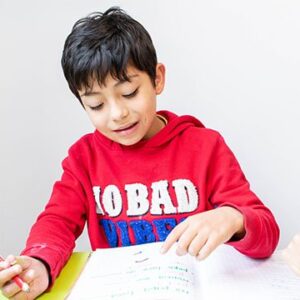 Niño escribiendo en cuaderno en terapia de psicopedagogía