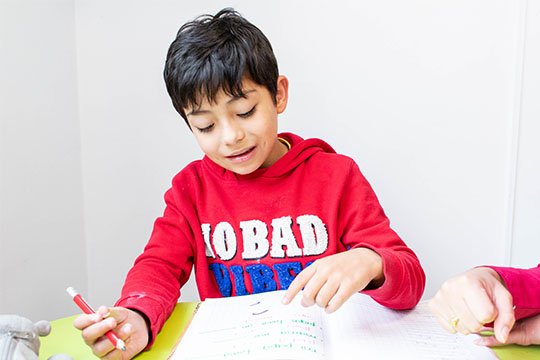 Niño escribiendo en cuaderno en terapia de psicopedagogía